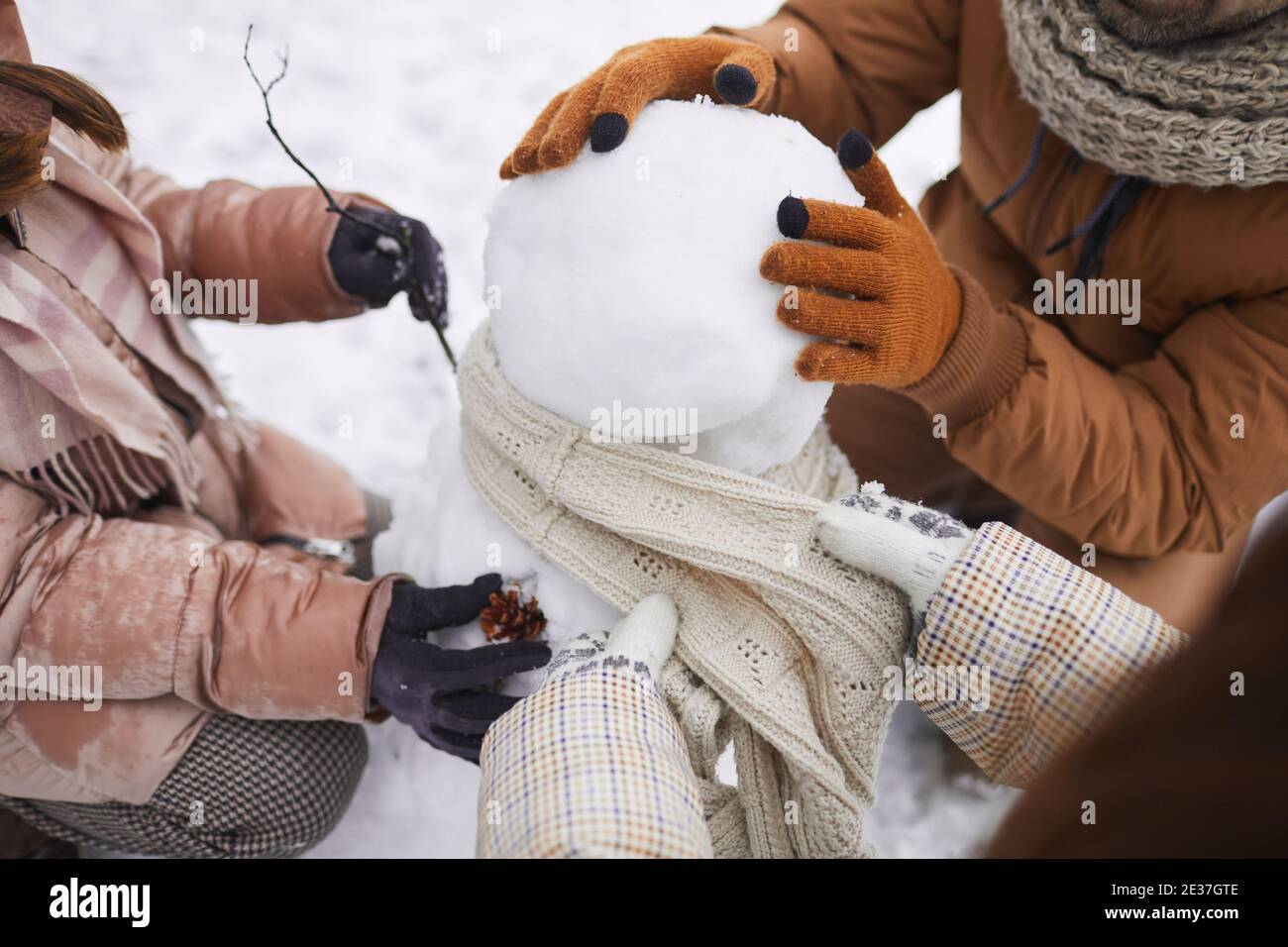 Primo piano di una famiglia felice irriconoscibile costruire pupazzo di neve insieme mentre godetevi le vacanze invernali all'aperto Foto Stock