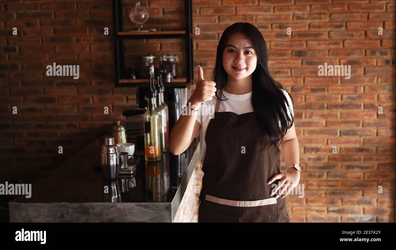 Giovane donna asiatica barista indossare grembiule OK gesto Foto Stock
