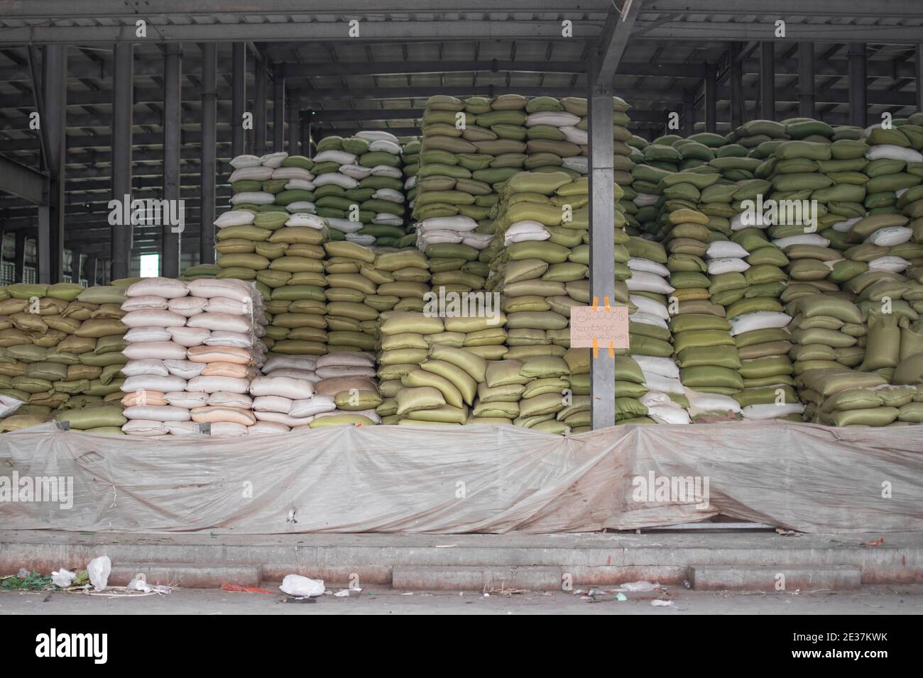 Sacchetti verdi e bianchi di riso accatastati alti ad a. Magazzino locale vicino Yangon in Myanmar Foto Stock