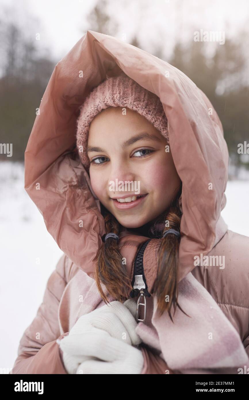 Verticale vista frontale ritratto di carina ragazza con giacca rosa e sorridendo con la macchina fotografica mentre ci si diverti a camminare all'aperto in inverno Foto Stock