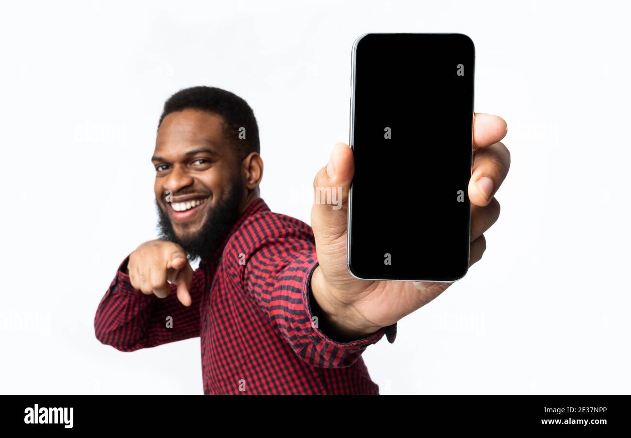 Guy nero allegro che mostra lo schermo del telefono alla fotocamera, sfondo bianco Foto Stock