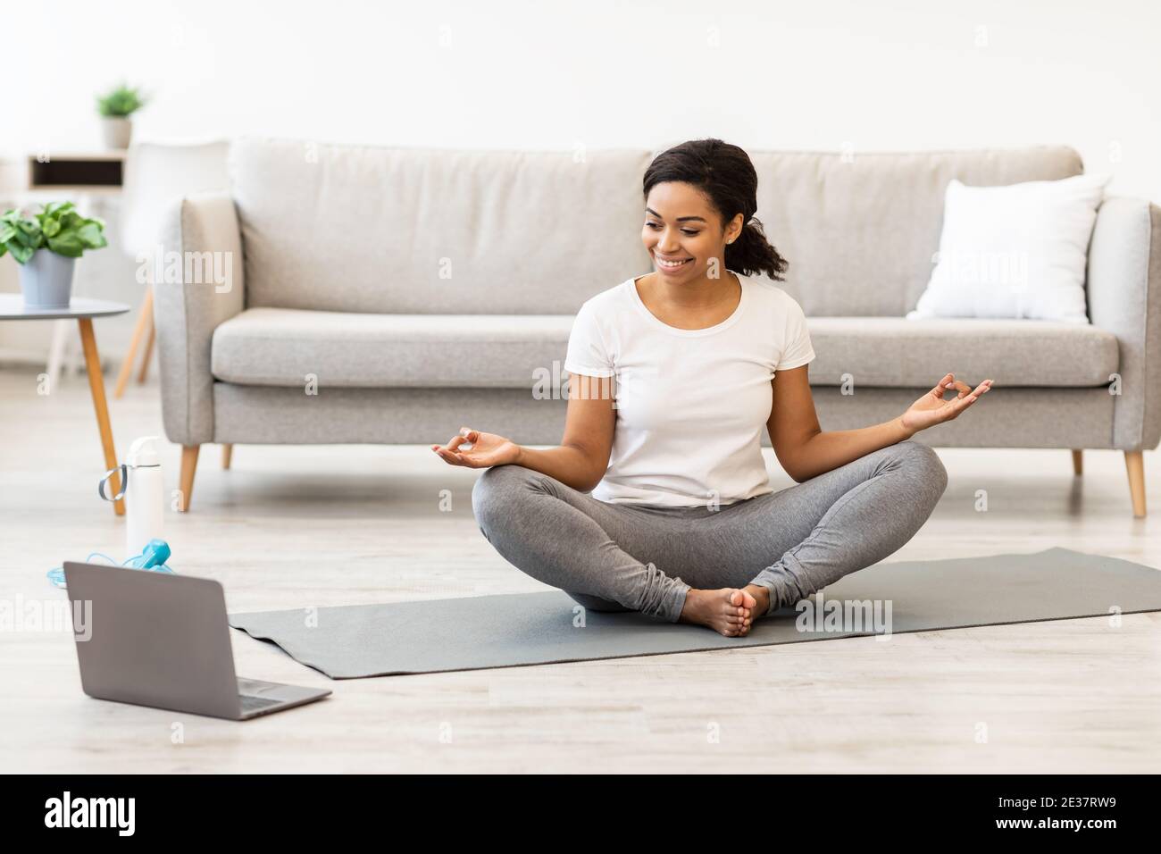 Donna nera che pratica yoga avendo tutorial online sul computer portatile Foto Stock