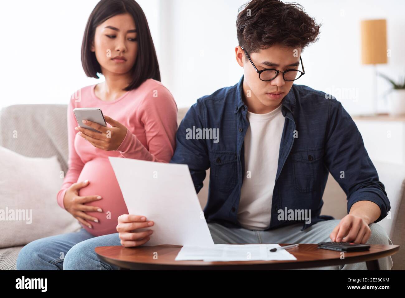 Ha interessato la coppia asiatica che calcola le spese guardando le fatture a casa Foto Stock