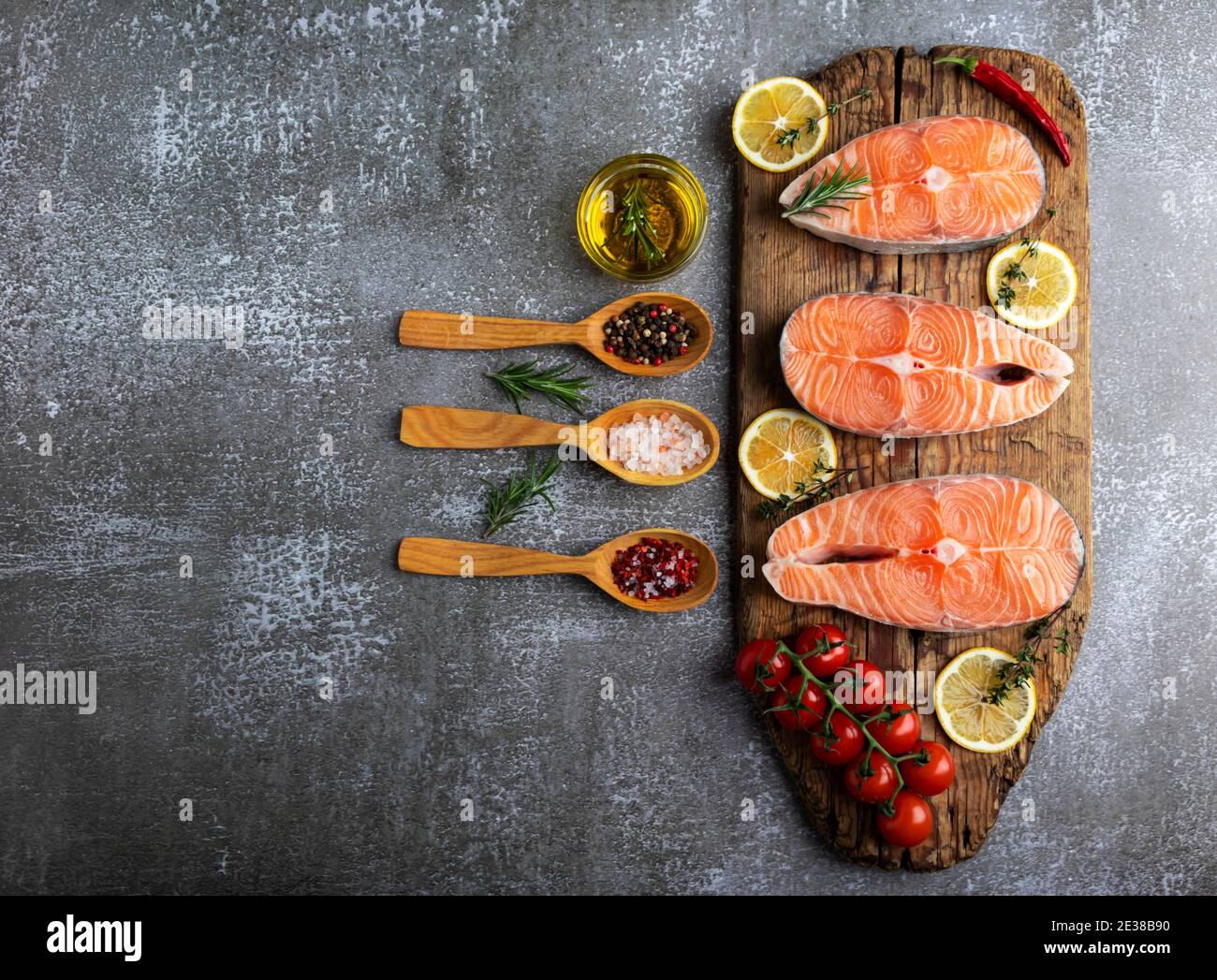 tre trote crude di pesce bistecca, salmone e spezie su tavola di legno, sfondo scuro Foto Stock