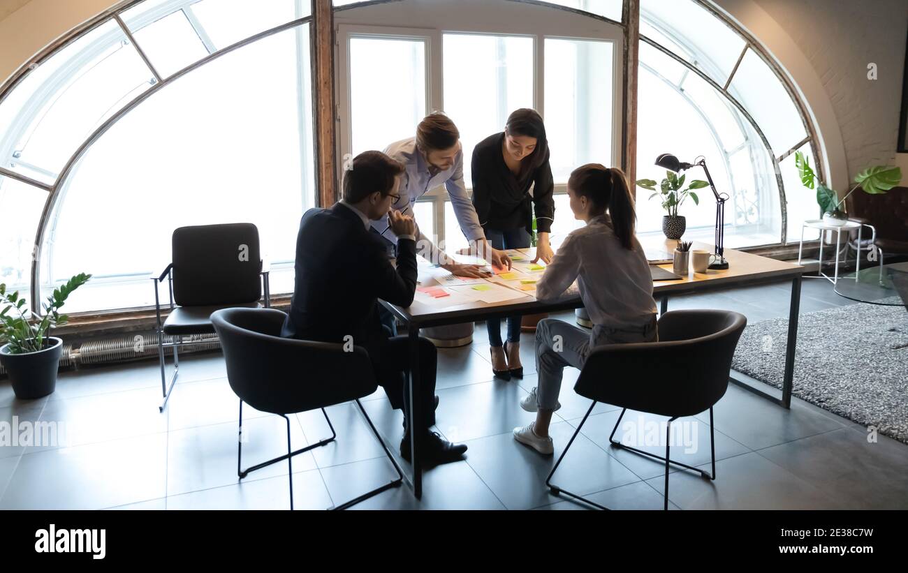 Dipendenti diversi che lavorano con documenti di progetto, utilizzando carte adesive Foto Stock