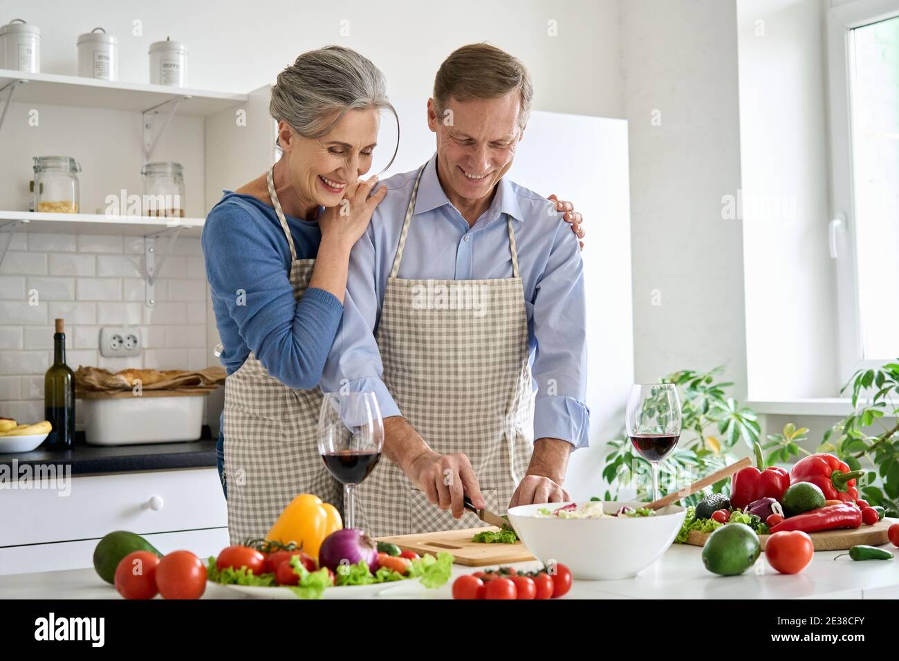 Felice anziana coppia che prepara insalata di verdure in cucina a casa. Foto Stock
