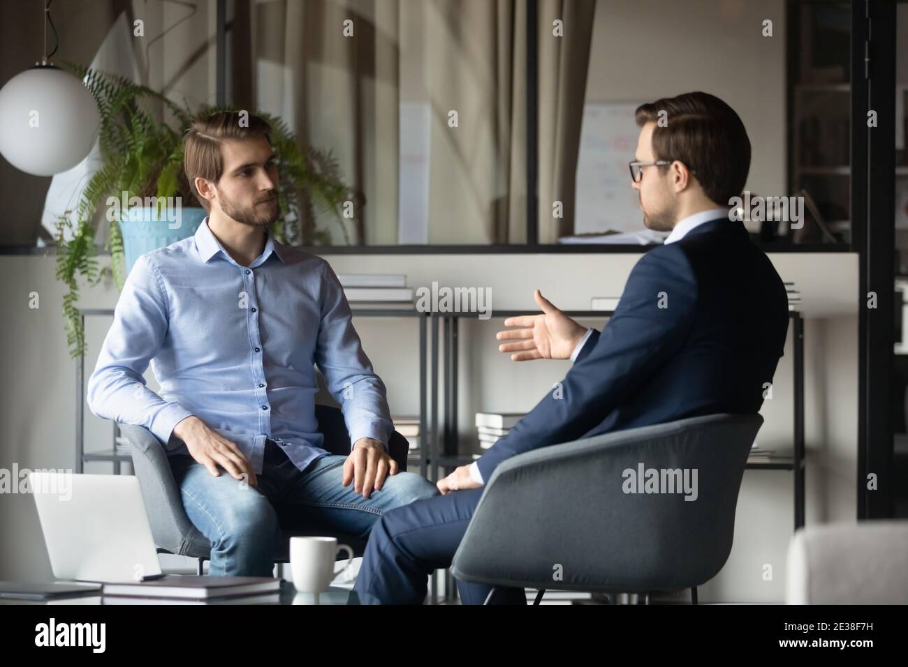 Colleghi uomini d'affari che discutono di strategia di progetto, seduti in un ufficio moderno Foto Stock