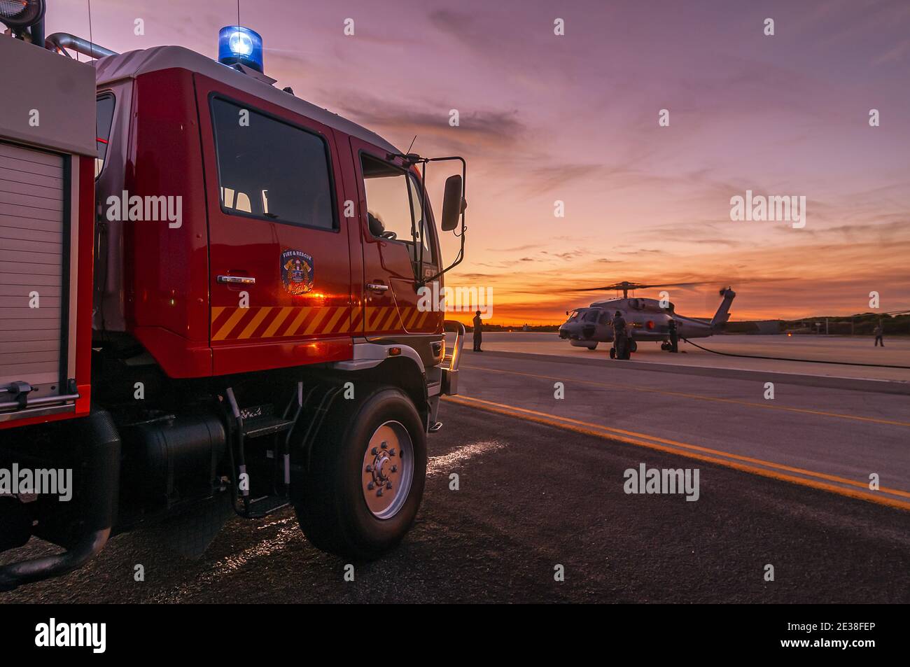 Un equipaggio militare dei vigili del fuoco si prepara mentre un elicottero Sikorsky S70B Seahawk si spegne presso una base aerea al tramonto. Foto Stock