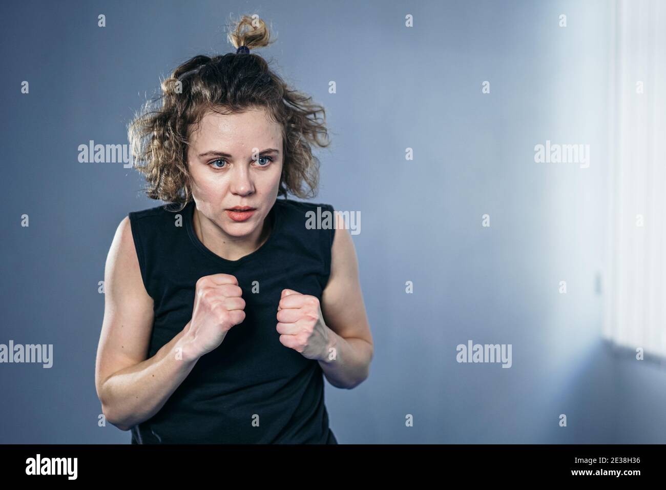 Il combattente femminile lancia i pugni direttamente nella macchina fotografica. La donna atleta taekwondo colpisce colpi nitidi e veloci, guardando direttamente nella fotocamera, movimento veloce Foto Stock