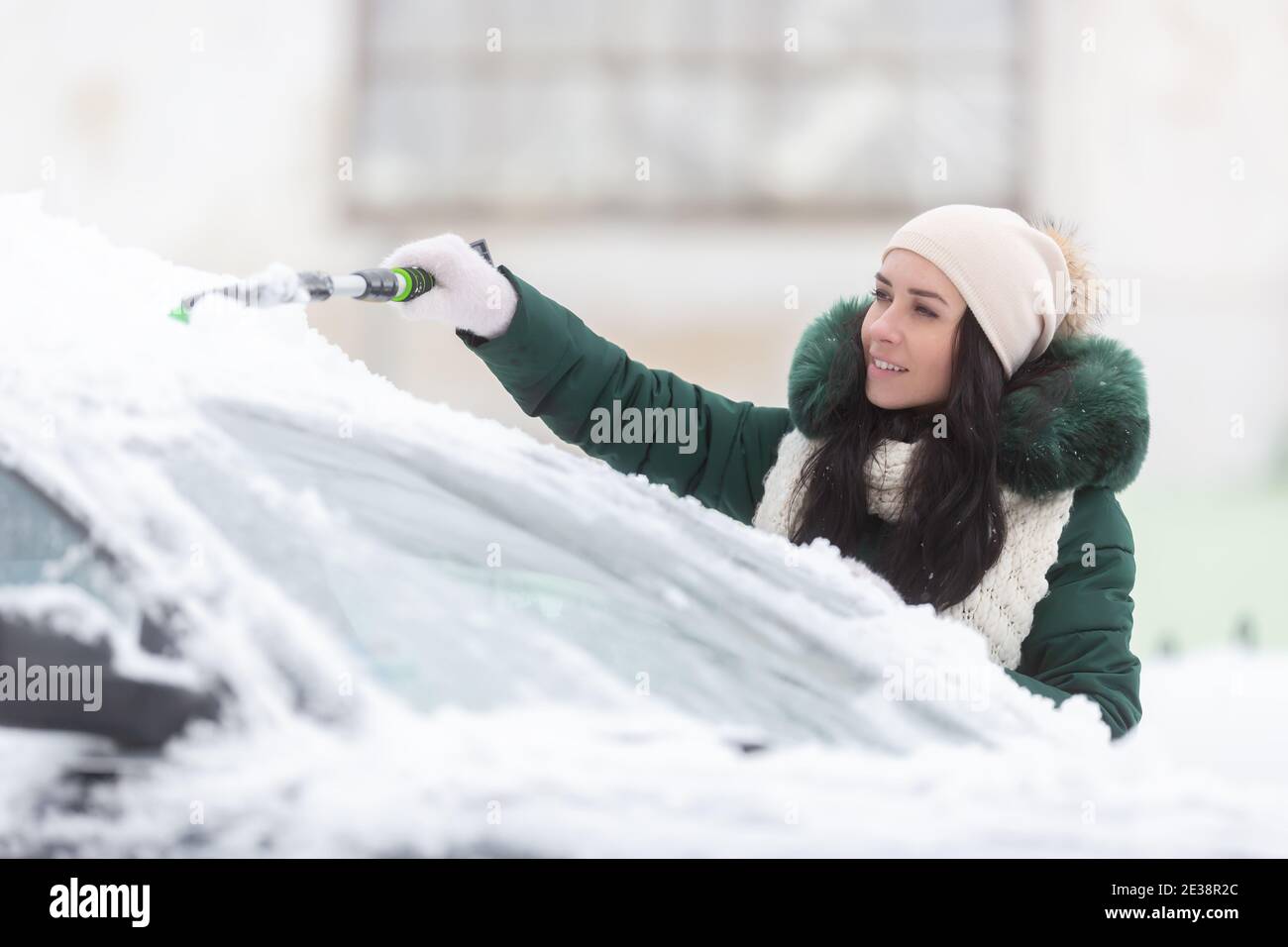 La rimozione della neve dalla vettura è solo una parte per una buona visibilità in inverno che deve essere seguita dalla raschiatura del ghiaccio dai parabrezza. Foto Stock