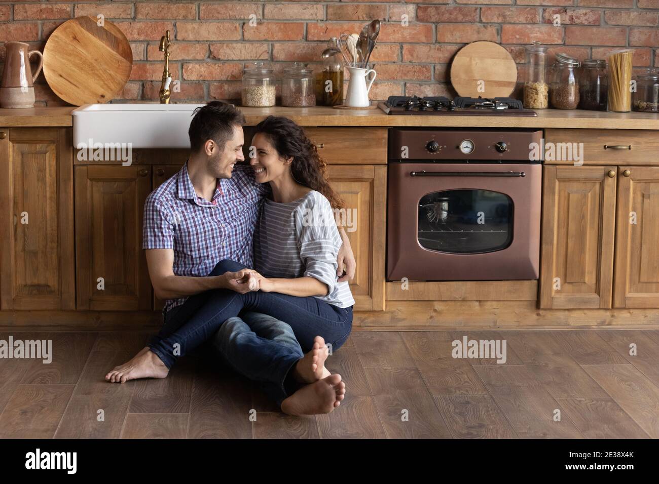 Felice coppia millenaria rilassarsi abbracciando in propria cucina Foto Stock