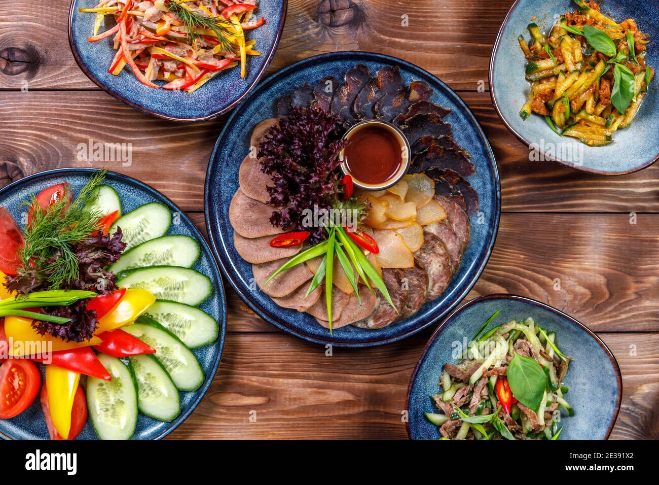 Disposizione piatta di vari piatti con verdure a fette, tagli di carne, insalate su fondo di legno marrone. Foto Stock