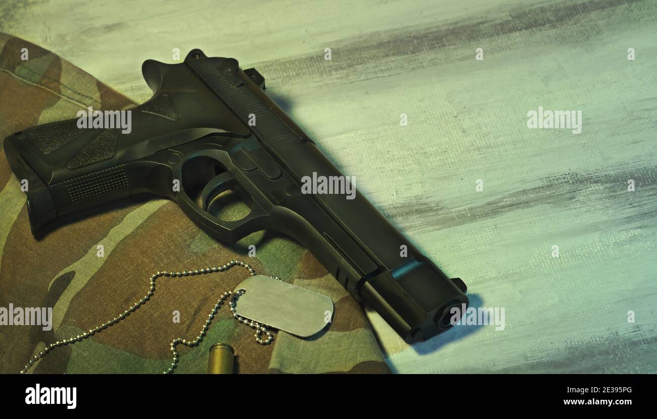Concetto di fotografia militare con una pistola una targhetta di identificazione in metallo un tessuto di camo e un proiettile su un legno bianco piastra con spazio per la copia del testo Foto Stock