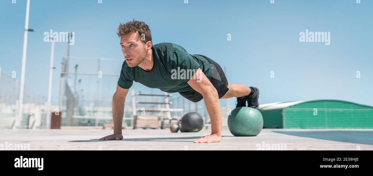 Fitness uomo banner panorama. Atleta forza allenamento spingere in su gambe equilibranti sulla palla di medicina per allenamento avanzato corpo esercizi di spinta-up pavimento Foto Stock