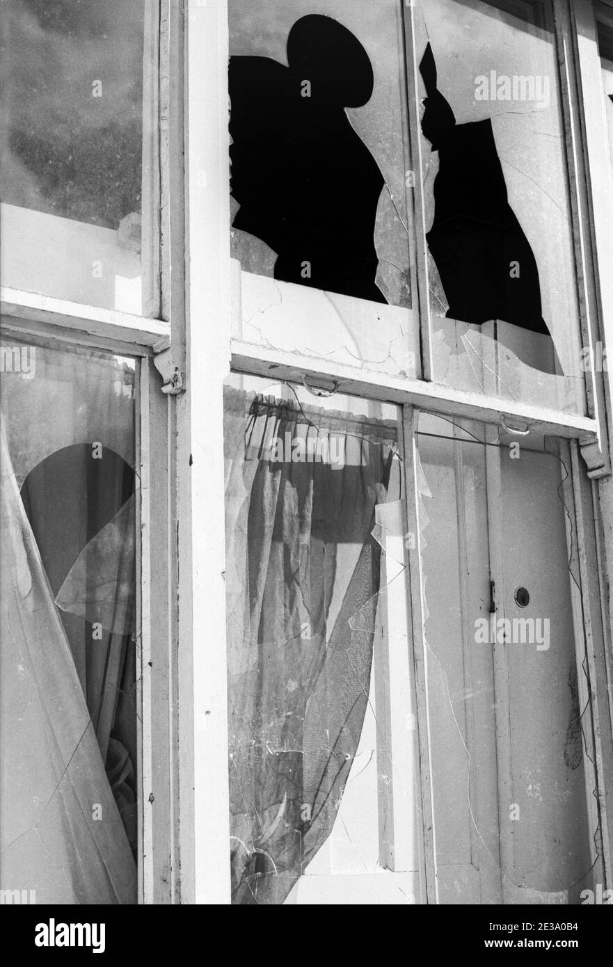 UK, West London, Notting Hill, 1973. Rundown e faticosamente grandi case a quattro piani stanno iniziando ad essere restaurate e ridecorate. Vetro della finestra rotto nella casa accanto al Talbot Tabernacle ingresso laterale in Powis Gardens Foto Stock