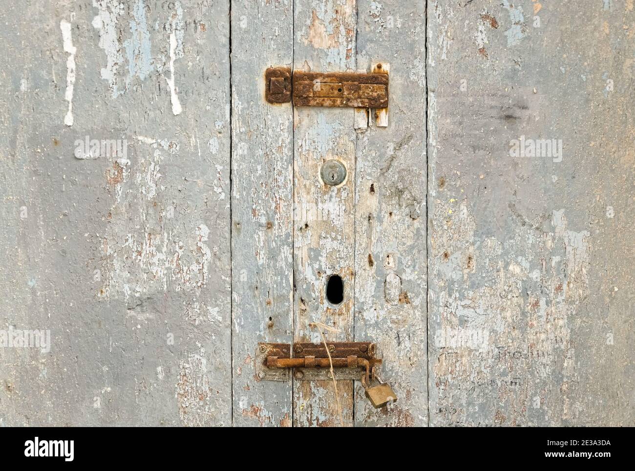 una porta in legno invecchiata, con serrature arrugginite che suggerisce tempi passati Foto Stock