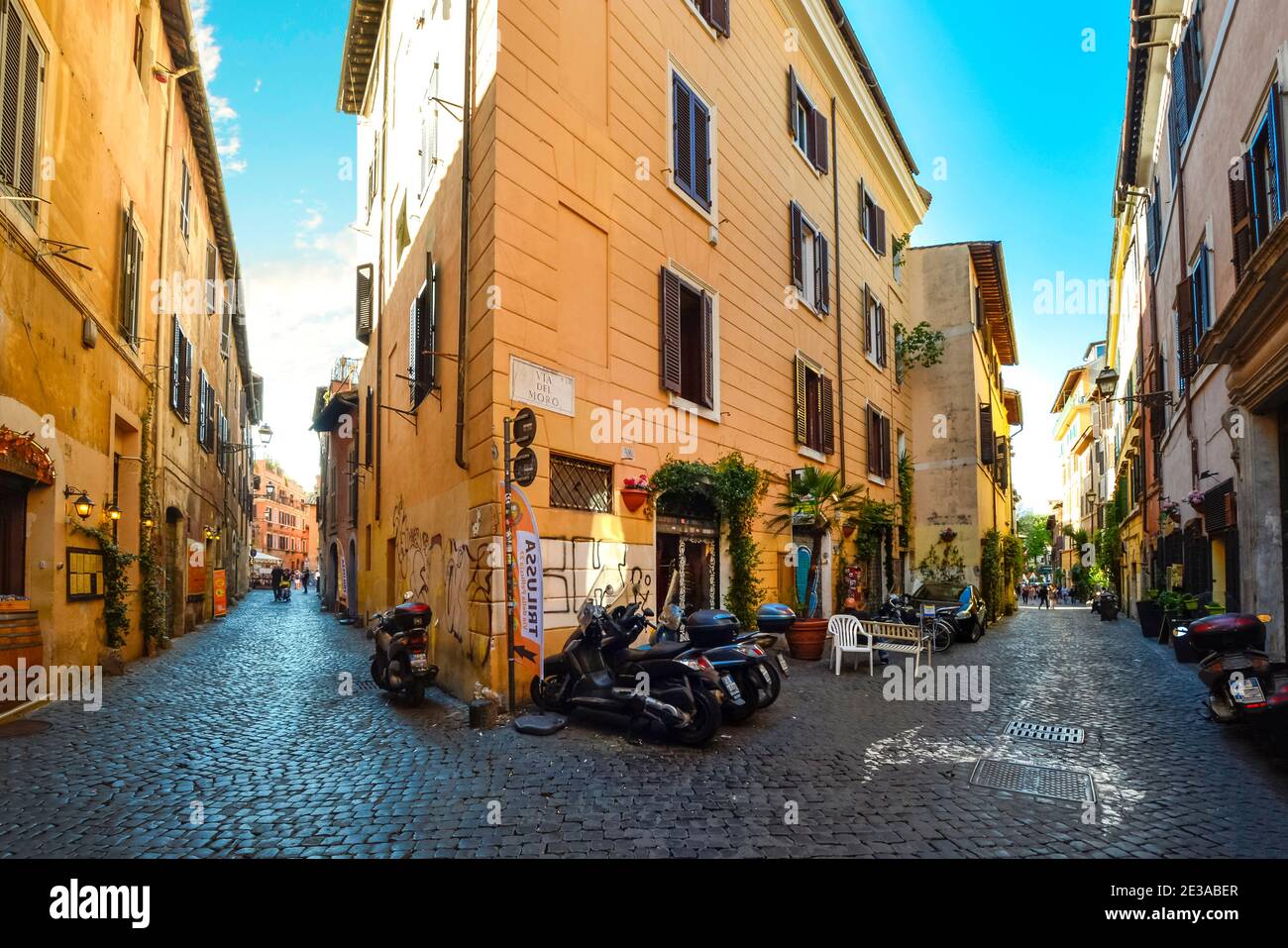 Pittoresca e colorata strada acciottolata con moto parcheggiate e negozi nel quartiere Trastevere di Roma. Foto Stock