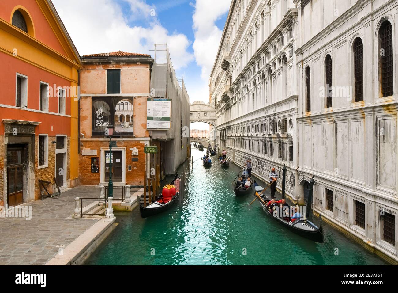 Un gondoliere veneziano con una famiglia di turisti nella sua gondola, manzi passato una piccola piazza vicino al Ponte dei Sospiri a Venezia, Italia Foto Stock