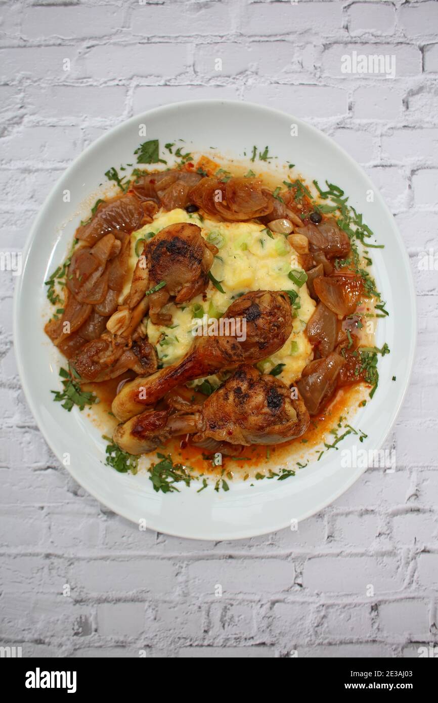 Cosce di pollo da vicino brasate con cipolle di macellaio servite con purè di patate alle erbe cucina greca moderna stampa di alta qualità Foto Stock