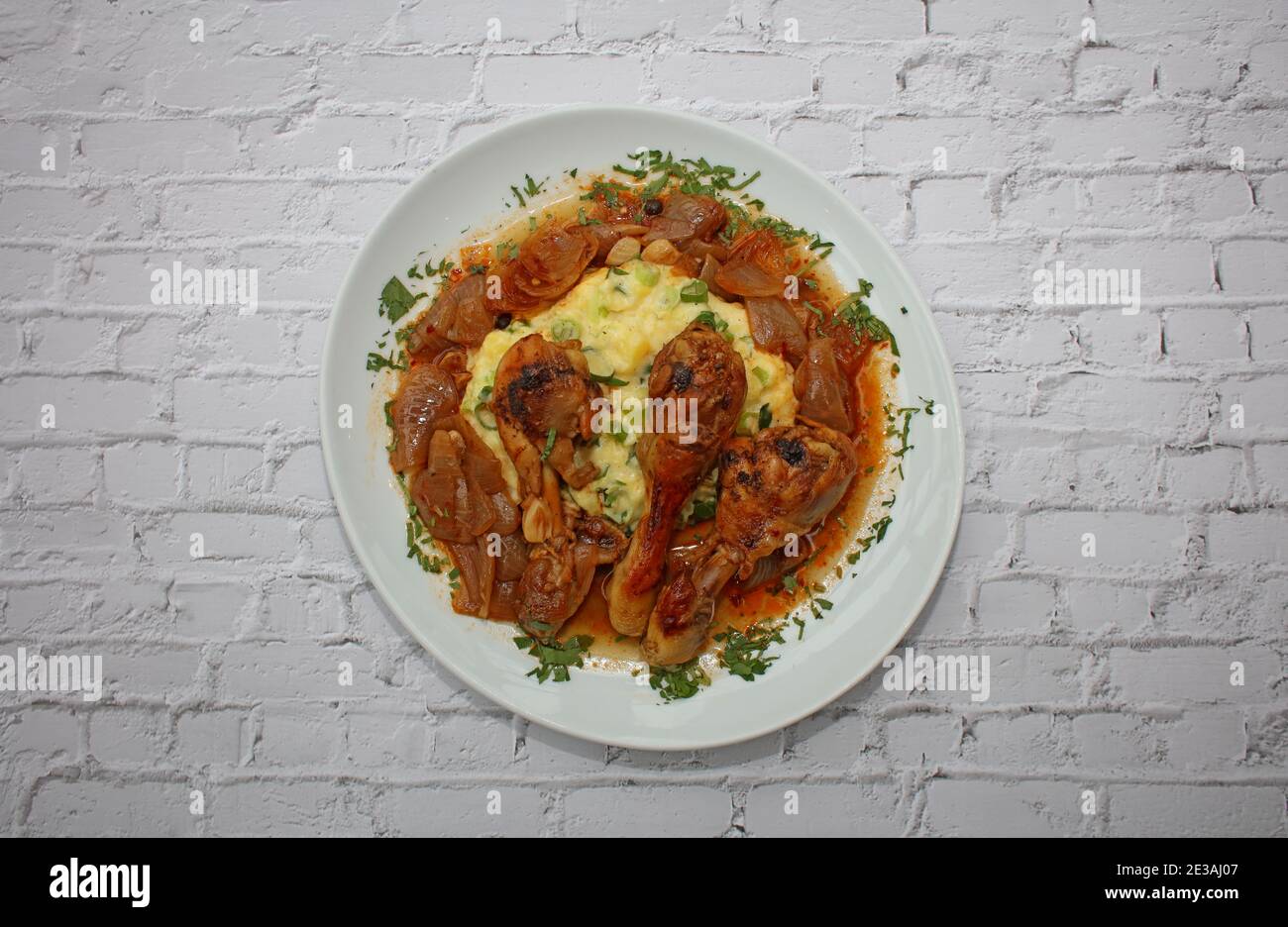 Cosce di pollo da vicino brasate con cipolle di macellaio servite con purè di patate alle erbe cucina greca moderna stampa di alta qualità Foto Stock