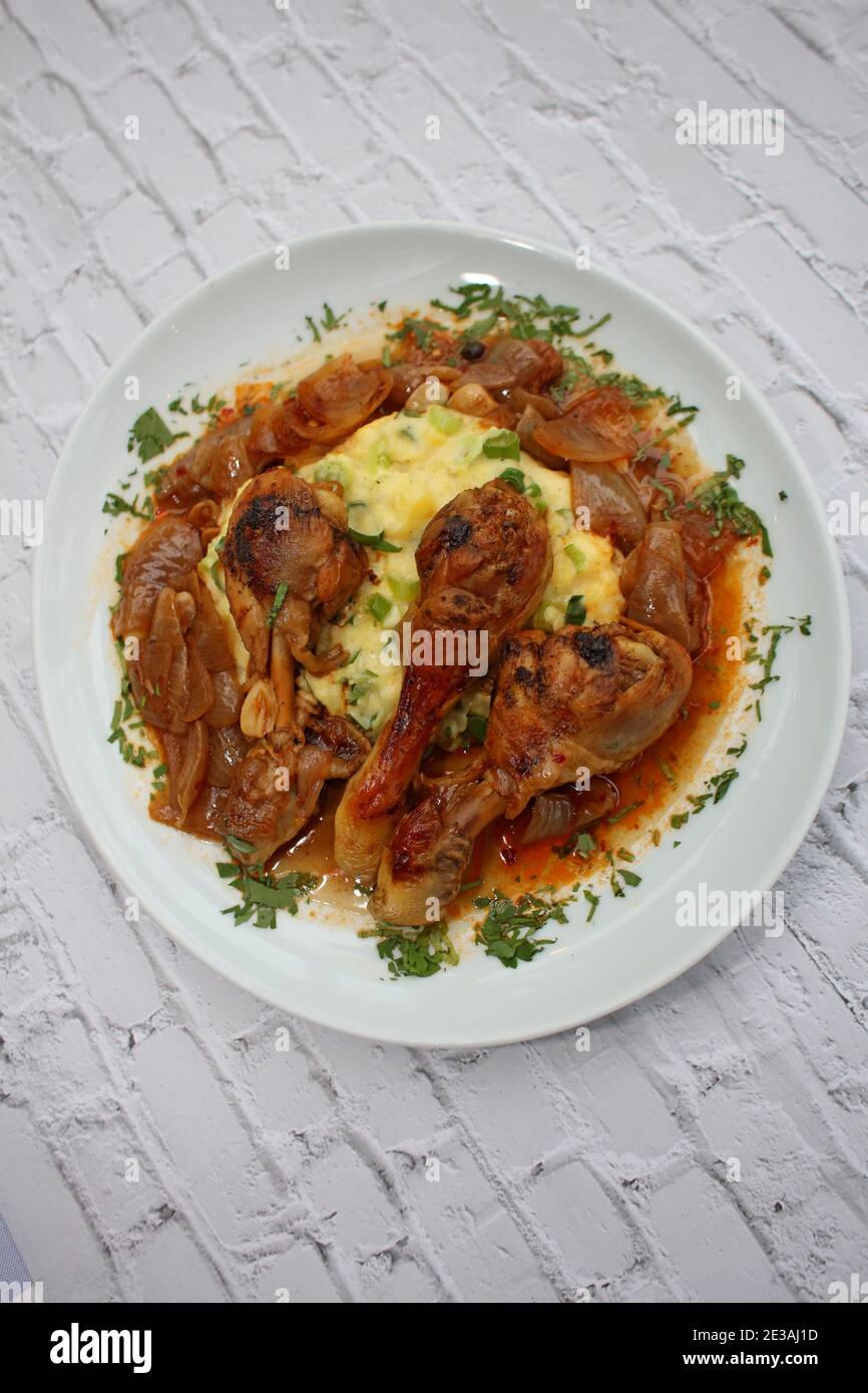 Cosce di pollo da vicino brasate con cipolle di macellaio servite con purè di patate alle erbe cucina greca moderna stampa di alta qualità Foto Stock