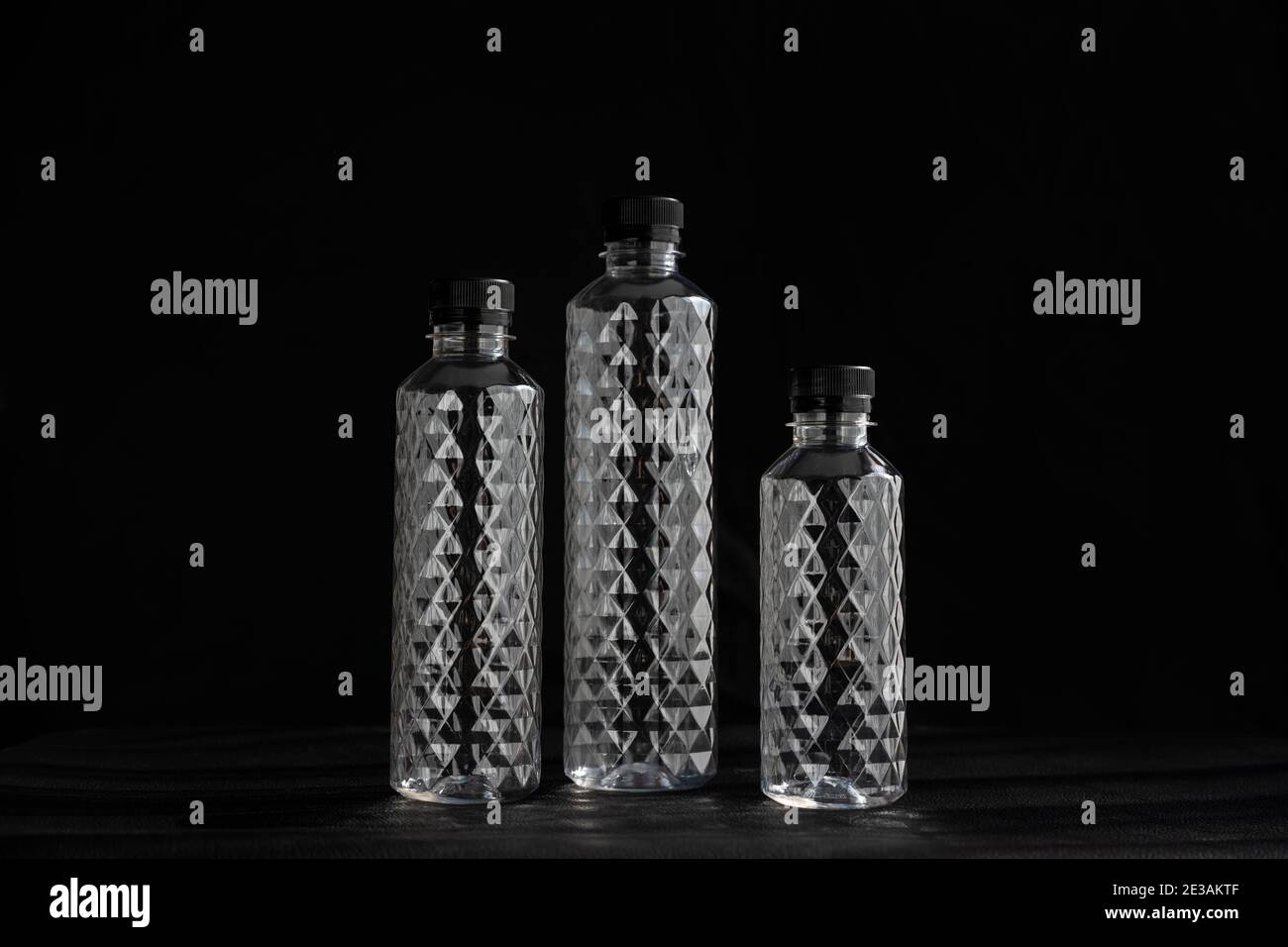 Bottiglie d'acqua di plastica di PET trasparenti e vuote sono state disposte alcune sfondi neri, il motivo di cristallo della bottiglia di glitter nel concetto di ricicla Foto Stock