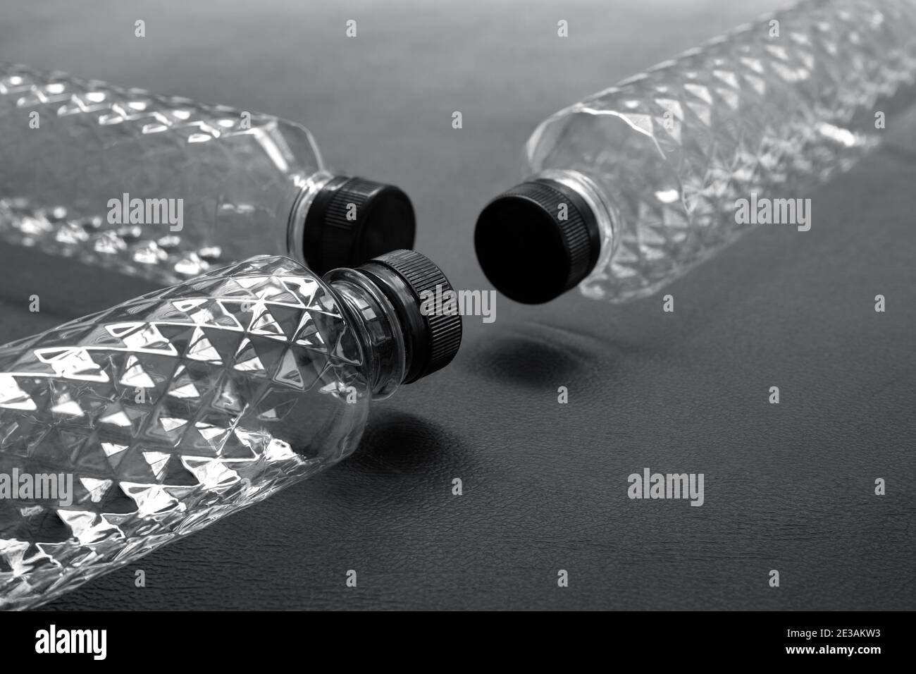 Bottiglie d'acqua di plastica di PET trasparenti e vuote sono state disposte alcune sfondi neri, il motivo di cristallo della bottiglia di glitter nel concetto di ricicla Foto Stock