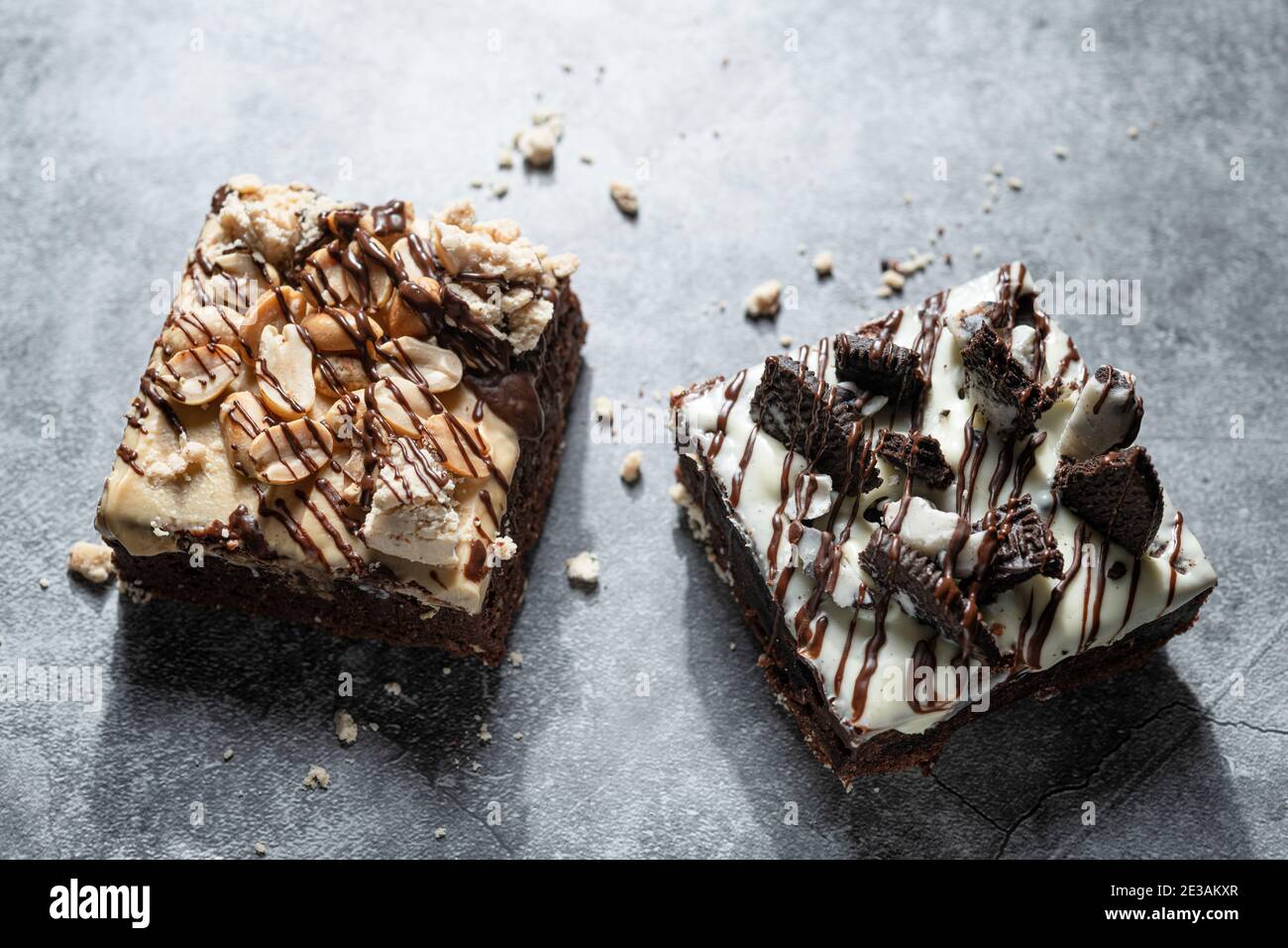 Vista dall'alto di un paio di deliziosi brownie gourmet fatti in casa con oreo e arachidi su rustico sfondo grigio. Foto Stock