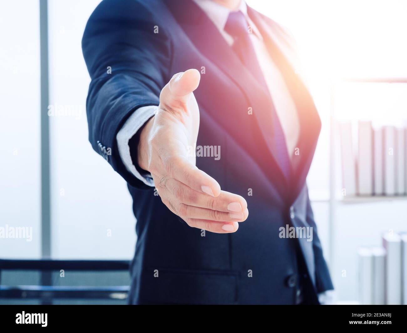 Un uomo d'affari con la mano aperta pronto a sigilli un affare su sfondo moderno dell'ufficio con luce di successo. Uomo d'affari in tuta tenere fuori la mano aspettando fo Foto Stock