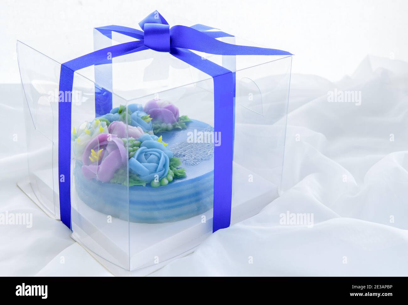 Torta minimale fatta da torta dolce dello strato del pandan e fiori graziosi della wite decorati in scatola di plastica su panno bianco. Dessert tailandese Foto Stock