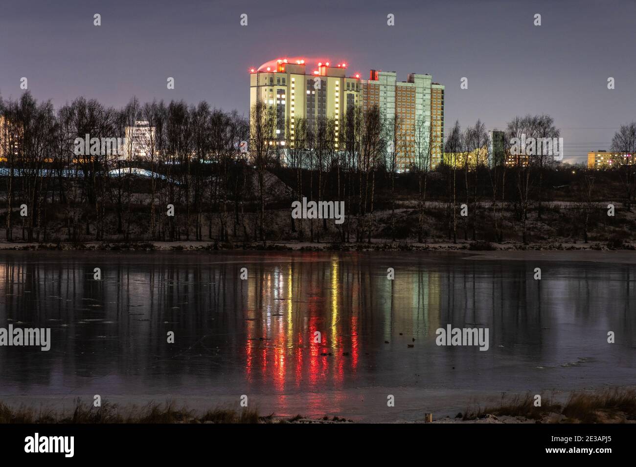 Alto edificio sulla riva del fiume Uvod e il suo riflesso sulla superficie ghiacciata dello specchio, Ivanovo, Russia. Foto Stock