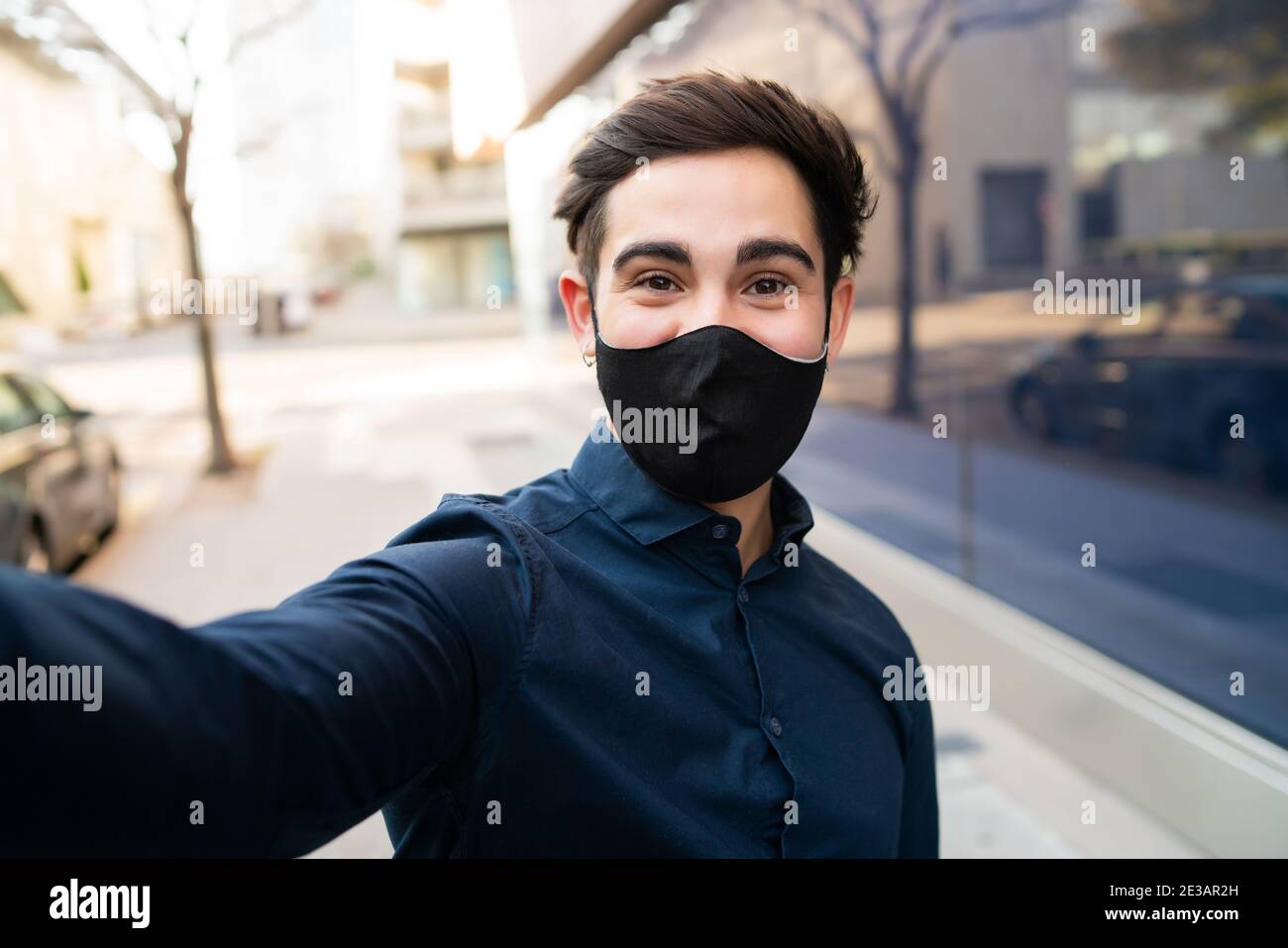 Ritratto di giovane uomo che prende un selfie all'aperto. Foto Stock