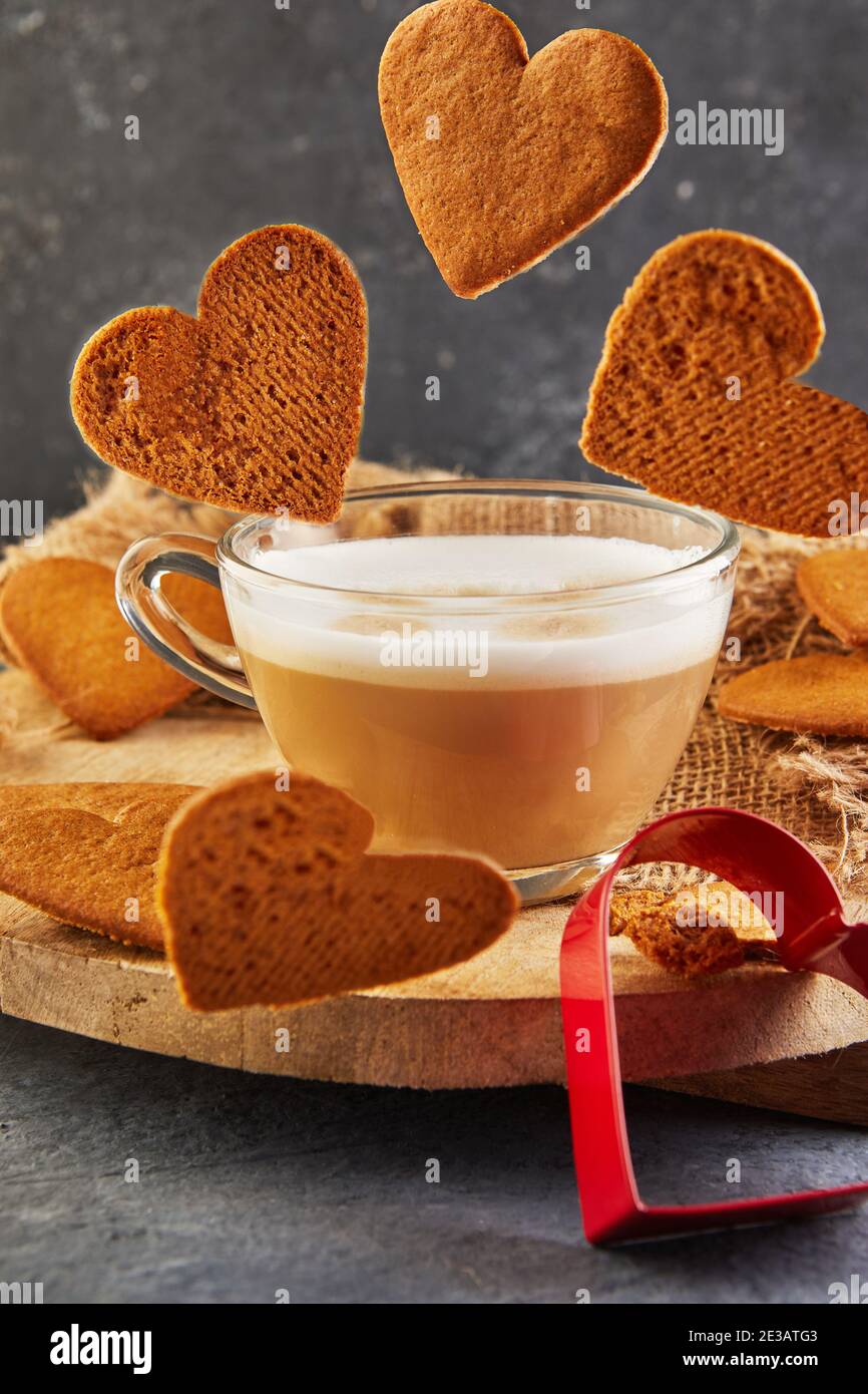 I biscotti di pan di zenzero a forma di cuore cadono in una tazza di caffè Foto Stock