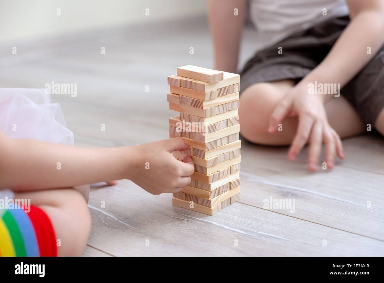 Due bambini raccolgono una torre di blocchi di legno sul pavimento. Foto Stock