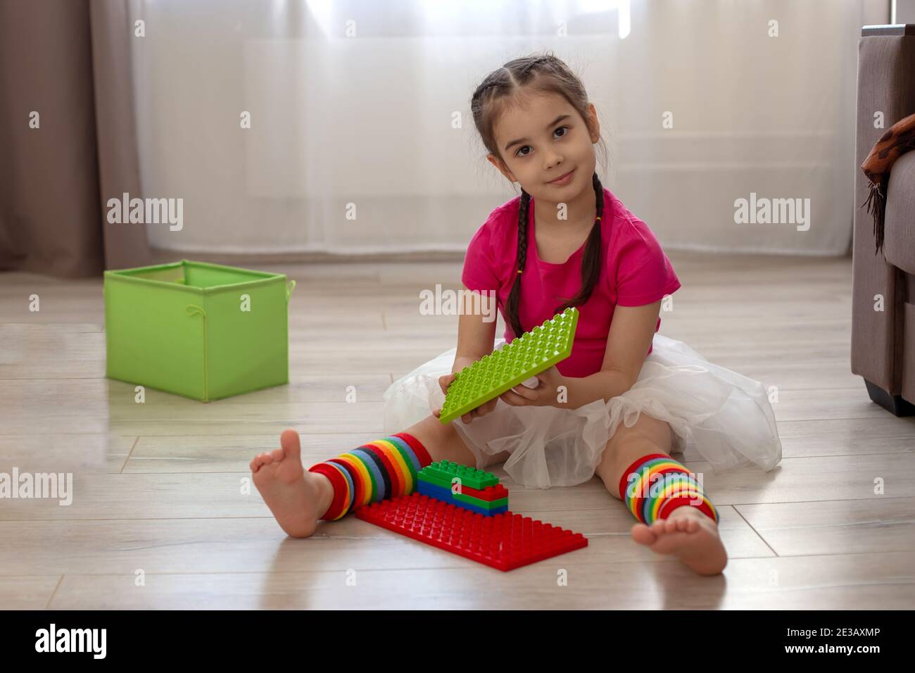 Gioco di ragazza con costruttore di plastica multicolore sul pavimento in camera Foto Stock