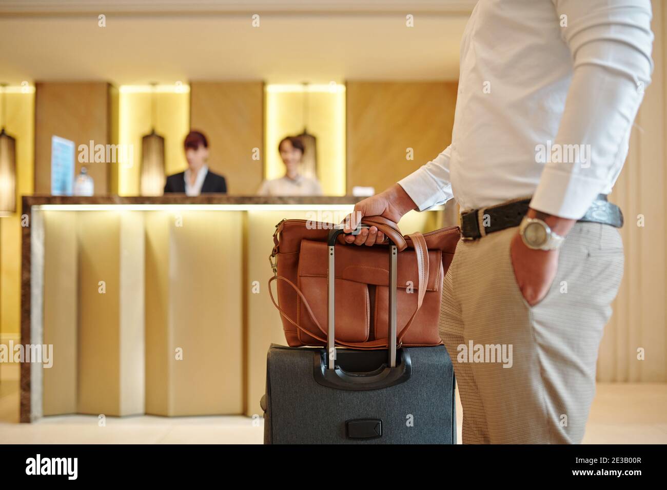 Immagine ritagliata degli ospiti dell'hotel che si trovano nella lobby con i bagagli dopo il check-in Foto Stock