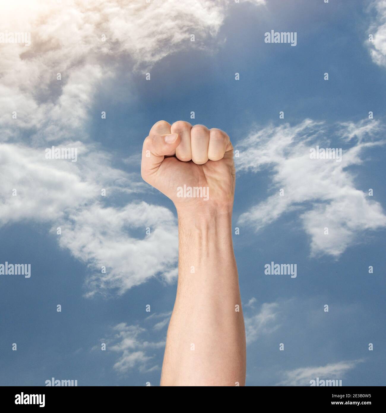 Pugno clenched nella mano Air.male alza pugno clenched di solidarietà. Protester che tiene la prima mano su cielo di bue. Mano che sale a clenche Sky.Man Foto Stock