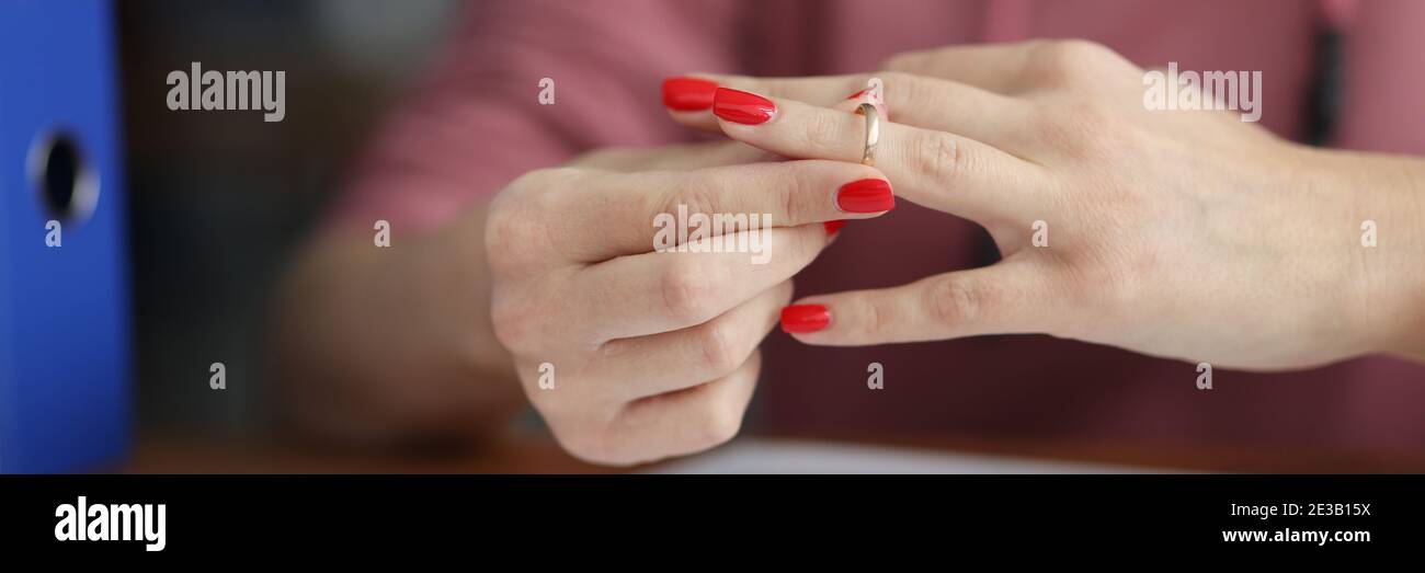 Donna che prende fuori il suo anello di nozze dal suo dito dentro primo piano della parte anteriore dei documenti Foto Stock