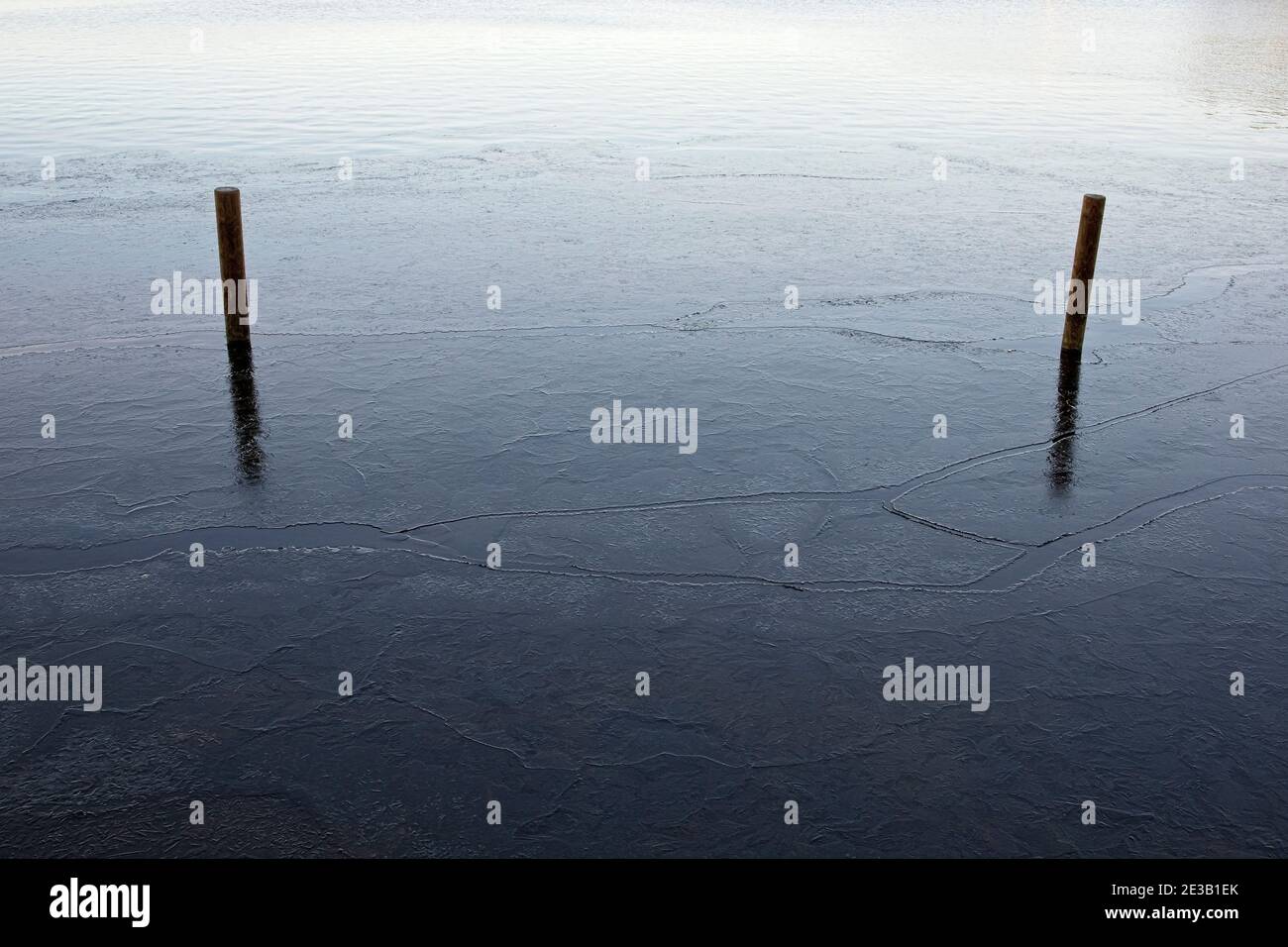 due pali di legno in un lago ghiacciato Foto Stock