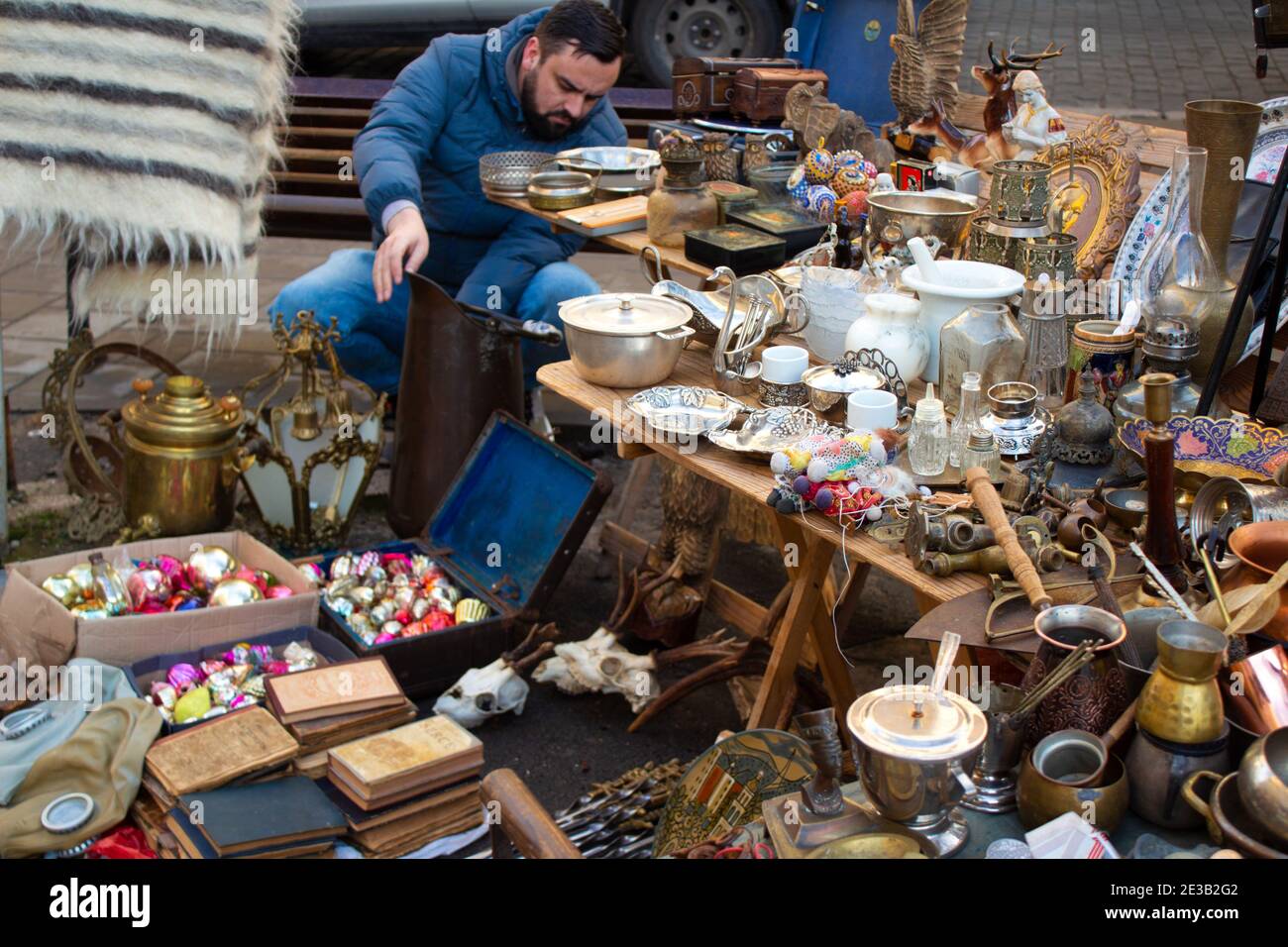 Un uomo che acquista diversi oggetti d'antiquariato sul mercato delle pulci - vecchie sculture d'argento vintage - cucchiai, coltelli, forchette, e altre cose d'annata. Ricordi da collezione Foto Stock