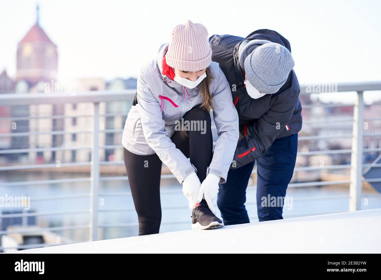 Coppia adulta che fa jogging in città in maschere durante il blocco Foto Stock