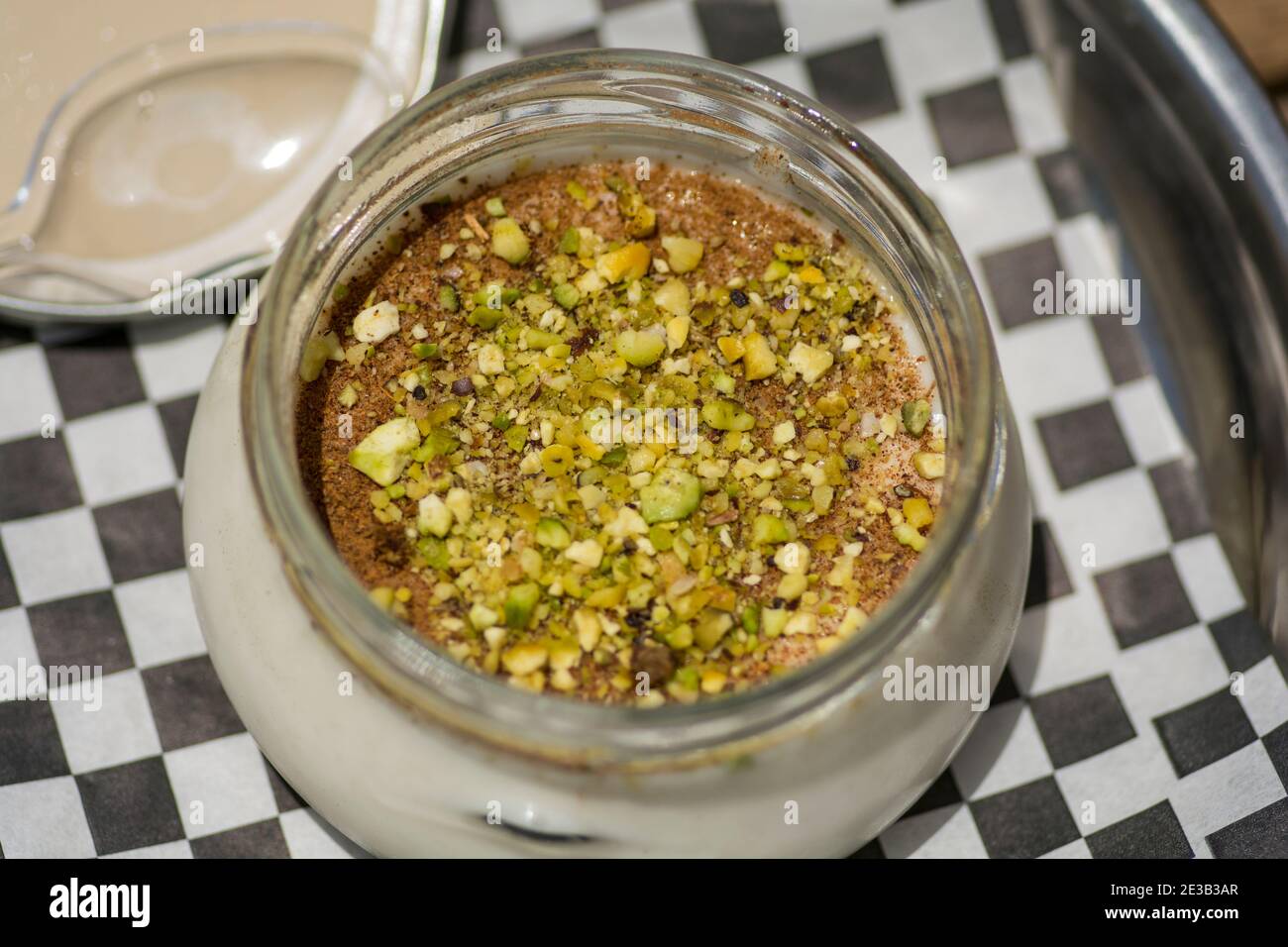 Vista dall'alto di una ciotola di Sutlac (Sütlaç) - dessert tradizionale turco aromatico, budino di riso cremoso con cannella e pistacchi, servito su un AN nero Foto Stock
