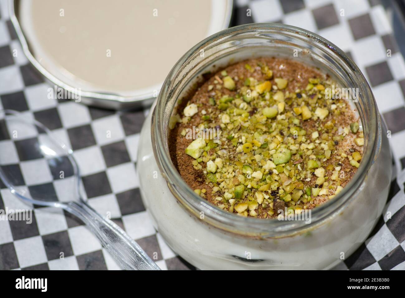 Vista dall'alto di una ciotola di Sutlac (Sütlaç) - dessert tradizionale turco aromatico, budino di riso cremoso con cannella e pistacchi, servito su un AN nero Foto Stock