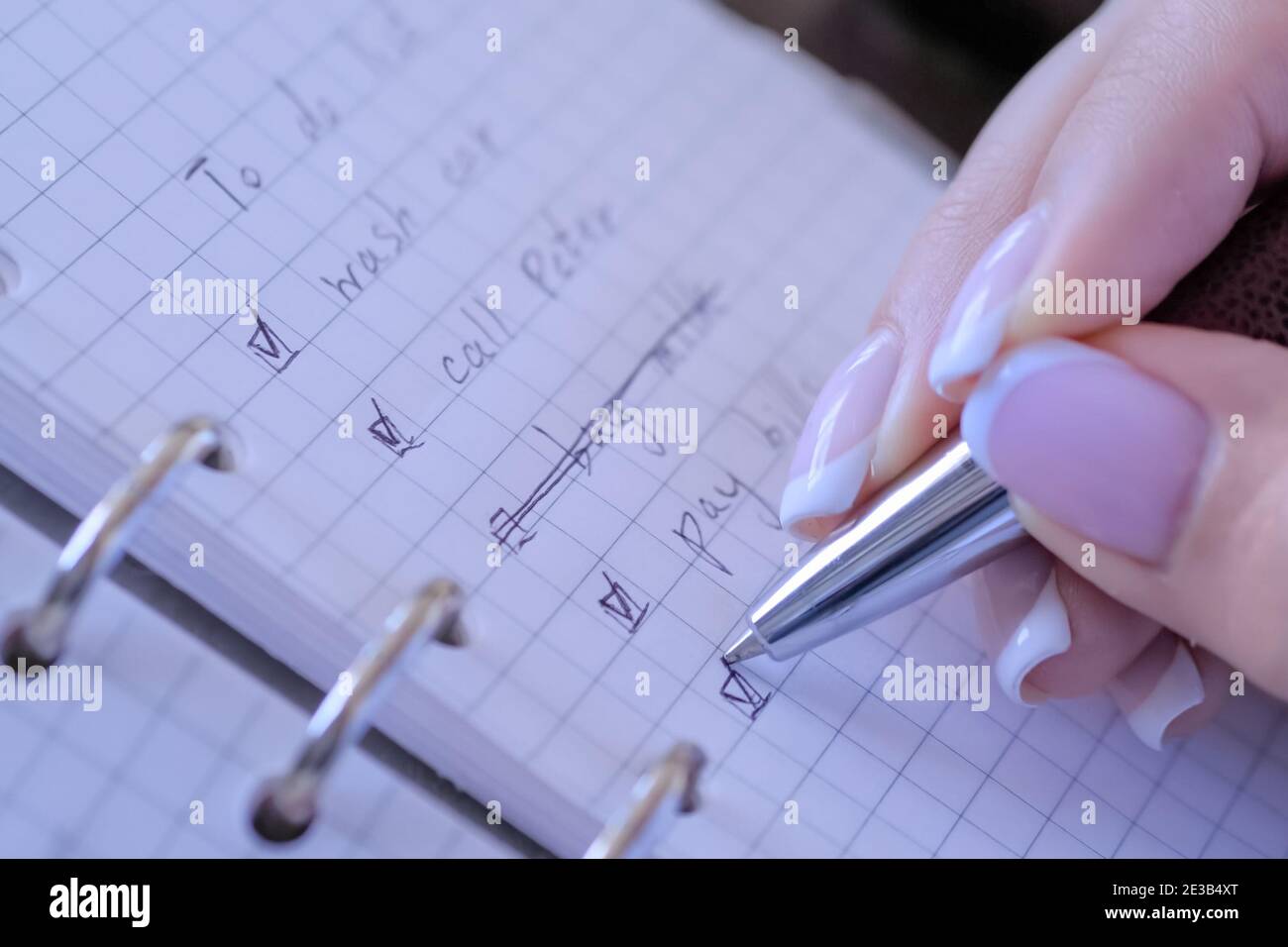 Donna mettendo il riferimento su caselle di controllo della Lista da fare in notebook - close up Foto Stock