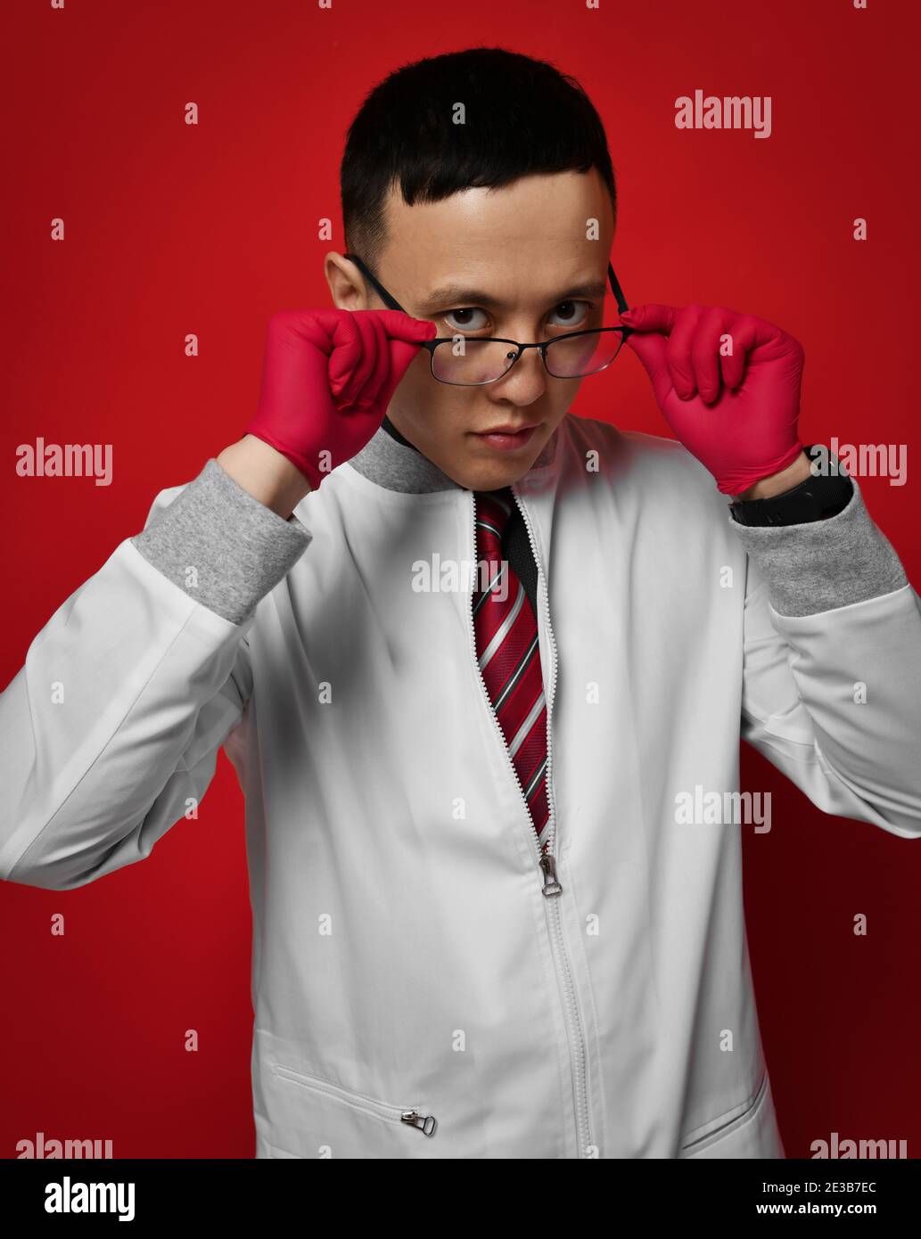 Ritratto di giovane medico urologo o proctologo in medicina abito e guanti che si mettono a togliere i suoi occhiali Foto Stock