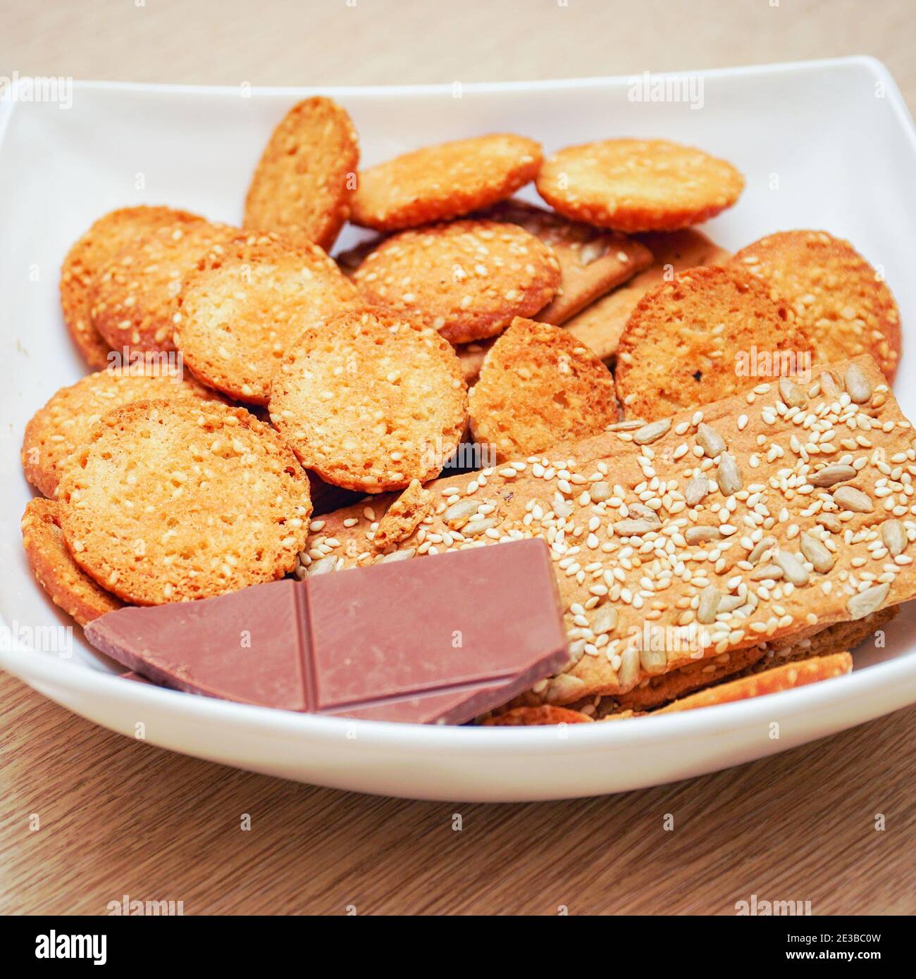 Biscotti e una barretta di cioccolato scuro su un piatto bianco Foto Stock