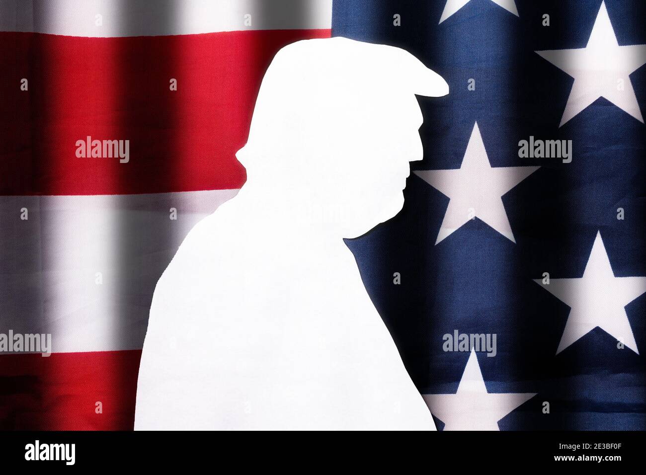 Taglio di carta bianca silhouette dell'ex presidente degli Stati Uniti sullo sfondo della bandiera americana. Disposizione piatta. La bandiera ha strisce scure repre Foto Stock