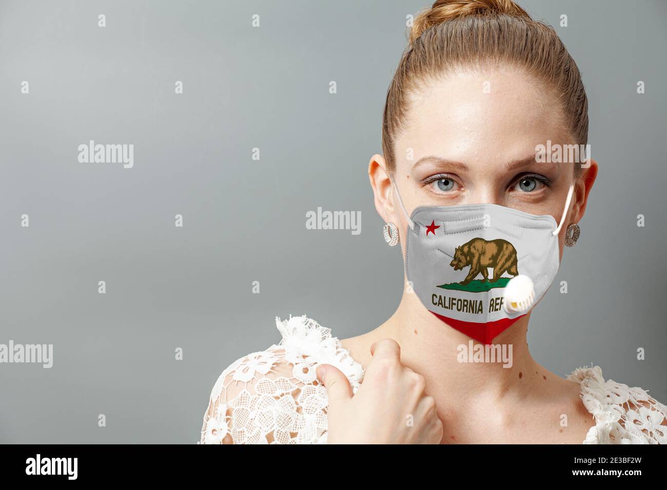 Ritratto di giovane donna che indossa maschera protettiva viso con bandiera Stati Uniti California per prevenire il coronavirus. Foto Stock