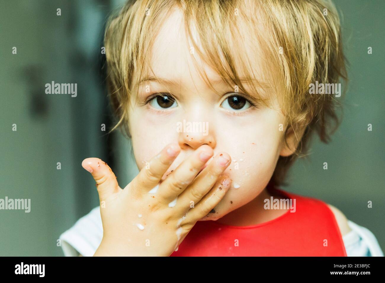 Un bambino adorabile ritratto mangiare torta di spugna di cioccolato Foto Stock
