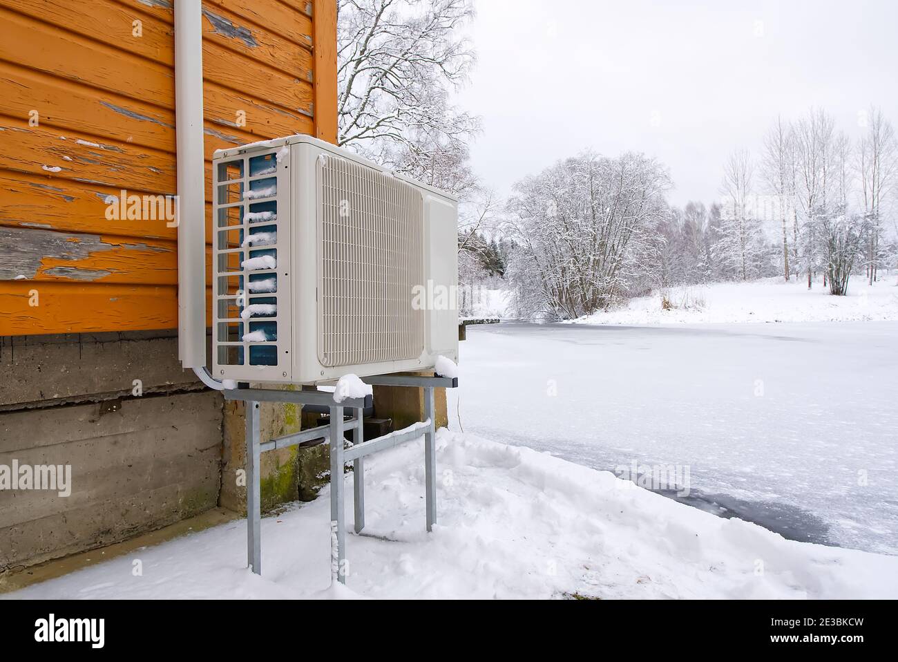 Pompa di calore aria-acqua nei pressi di una vecchia casa di legno in inverno. Pompa di calore aria-acqua primo piano Foto Stock